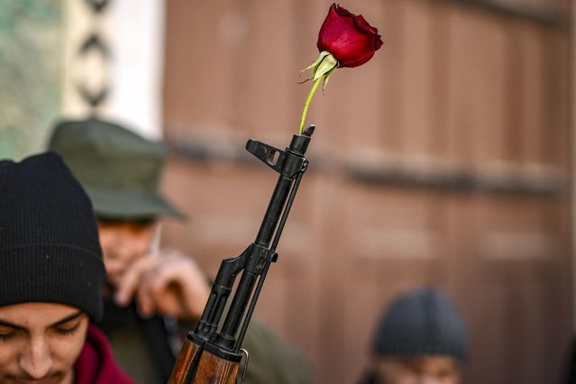 A rose is placed at the tip of the barrel of an assault rifle held by a Syrian rebel fighter before the first weekly Muslim Friday prayers since the ouster of president Bashar al-Assad at the Umayyad mosque in the old city of Damascus on December 13, 2024. Islamist-led rebels took Damascus in a lightning offensive on December 8, ousting president Bashar al-Assad and ending five decades of Baath rule in Syria. (Photo by Aris Messinis/AFP Photo)