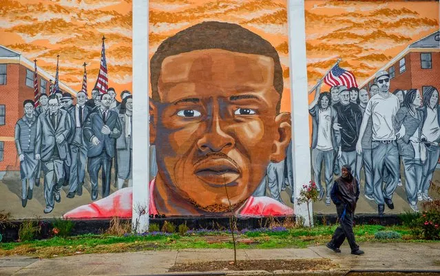 A man, who declined to offer his name, walks past a mural of Freddie Gray in the Sandtown-Winchester neighborhood of Baltimore, December 17, 2015. On Wednesday, Judge Barry Williams declared a mistrial in the case of Police Officer William Porter, one of six officer charged connection with the death of Freddie Gray. (Photo by Bryan Woolston/Reuters)