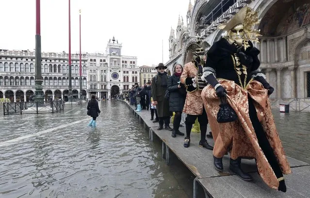 Masked revellers walk on raised platforms above flood waters during a period of seasonal high water and on the first day of carnival, in Venice February 1, 2015. (Photo by Stefano Rellandini/Reuters)