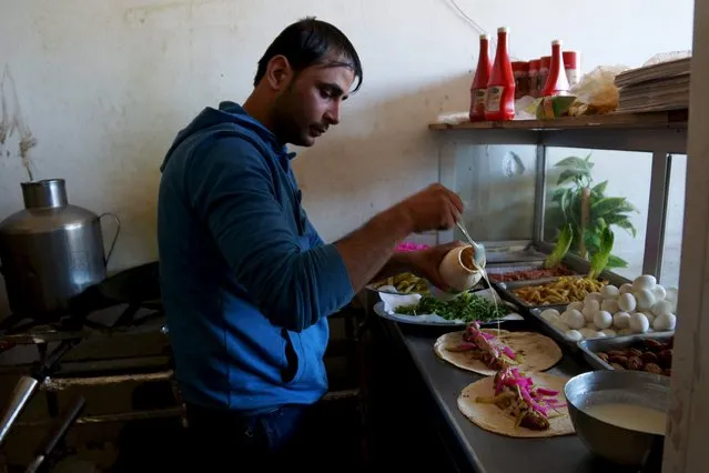 A man prepares a falafel sandwich inside a restaurant in Naemeh town located east of the city of Deraa, Syria December 22, 2015. Pictures taken December 22, 2015. (Photo by Alaa Al-Faqir/Reuters)