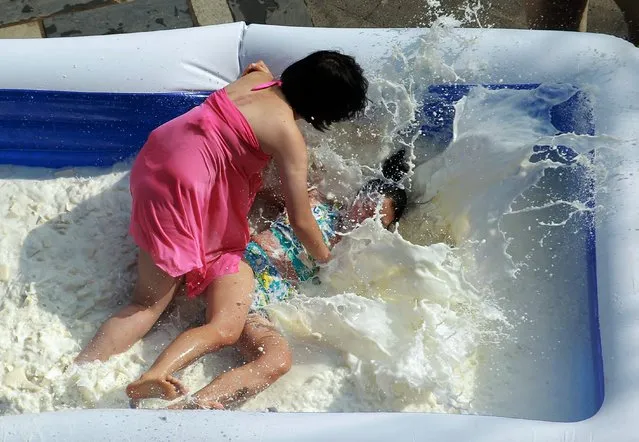 This picture taken on February 1, 2015 shows participants competing in a tofu (beancurd) wrestling competition in Fogang county, south China's Guangdong province. Participants, mostly women, fight it out in an inflatable pool which is filled with nearly two tons of fresh milk and tofu, in a promotion to attract tourists for the upcoming Chinese Lunar New Year holiday. (Photo by AFP Photo/Stringer)