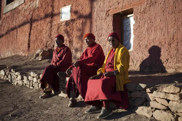 In this photograph taken on July 7, 2018, Indian Buddhist monks Nawang Tsultrim (L), 54, Lobzan Nyenda (C), 68, and Tashi Jamphel,71, sit in the afternoon sun while praying at Tnagyud Gompa monastery in Komik in Spiti Valley in the northern state of Himachal Pradesh. Many monks and followers came to the region after Tibet fell under Chinese rule almost 50 years ago. (Photo by Xavier Galiana/AFP Photo)
