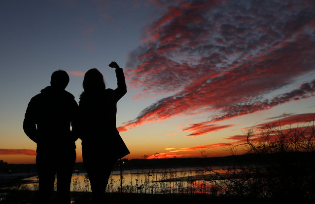 Kathleen O'Brien, of Portland, Maine, and Kathryn McBrady, of Scarborough, Maine, take in the view of a fiery winter sunset overlooking Back Cove, Thursday, January 7, 2016, in Portland, Maine. (Photo by Robert F. Bukaty/AP Photo)