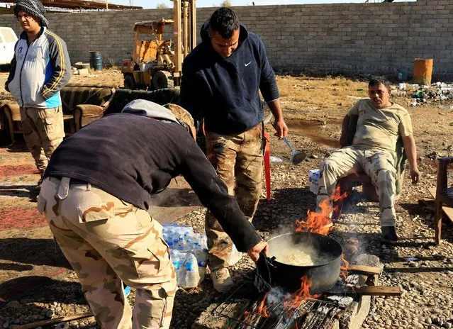 Iraqi security forces cook in the street of Gogjali neighborhood in Mosul, Iraq, December 4, 2016. (Photo by Thaier Al-Sudani/Reuters)