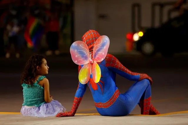 Genesis, 4, looks at a person wearing a costume of Spider-Man with butterfly wings, as they attend a march of the LGBT+ pride celebrations, in Ciudad Juarez, Mexico on June 19, 2022. (Photo by Jose Luis Gonzalez/Reuters)