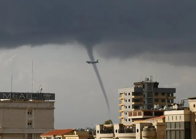 A waterspout forms over the Mediterranean Sea as a passenger jet descents to land at Beirut-Rafic Hariri International Airport in Beirut January 1, 2015. (Photo by Jamal Saidi/Reuters)