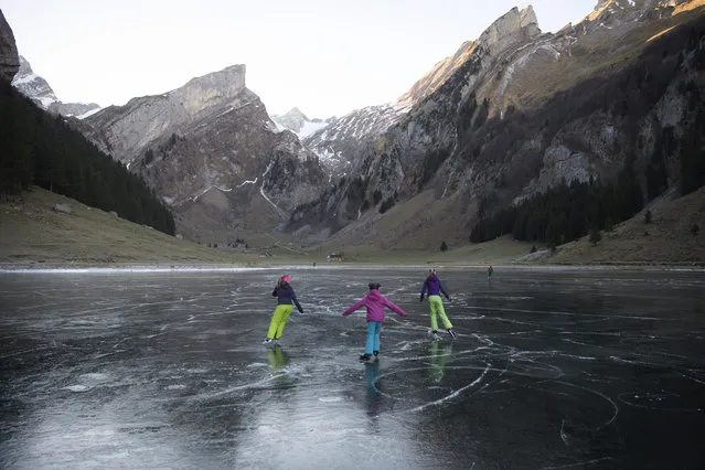 People enjoy ice skating on the black ice of the Seealpsee, in Schwende, canton of Appenzell Innerrhoden, Switzerland, 14 December 2016. (Photo by Gian Ehrenzeller/EPA)