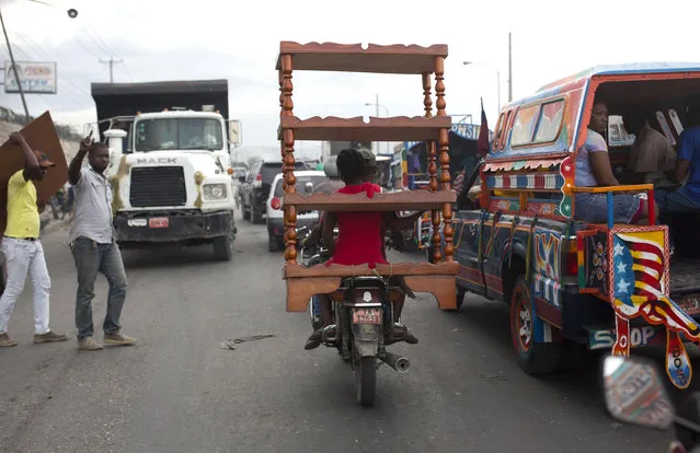 A motorcycle taxi passenger transports furniture through a busy street in Port-au-Prince, Haiti, Thursday, September 20, 2018. (Photo by Dieu Nalio Chery/AP Photo)