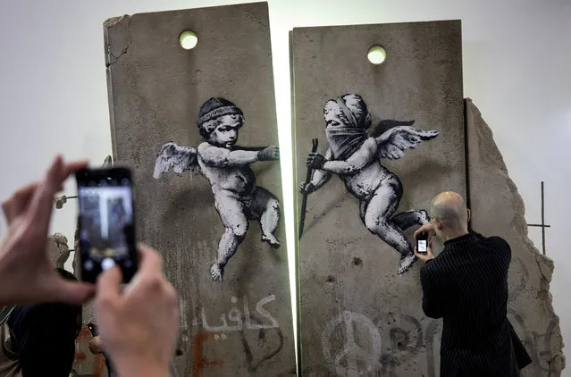 Visitors take photographs of the “replica separation barrier” created by British street artist Banksy as it stands on display at the Palestine tourist stand at the World Trade Fair at the Excel centre in London, Britain November 5, 2018. (Photo by Simon Dawson/Reuters)