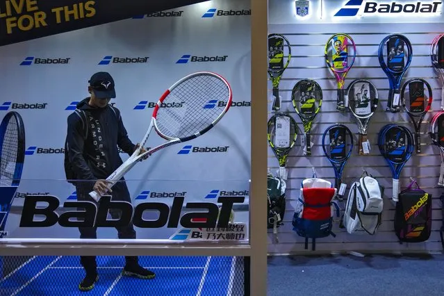 A man tries out a giant tennis racquet at a merchandise store at Qizhong Forest Sports City Tennis Center in Shanghai, China, Friday, October 13, 2023. China's exports and imports both fell in September from a year earlier, though they contracted at a slower pace even as global demand remained muted. (Photo by Andy Wong/AP Photo)
