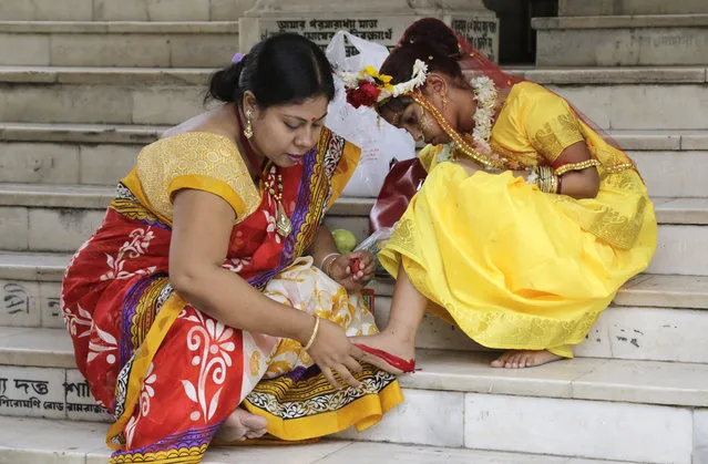 A Hindu woman decorates the sole of her daughter's feet with vermillion for her to participate in a ceremony where young girls are worshipped as “Kumari”, or living goddess, during Ram Navami festival, at a temple in Kolkata, India, Saturday, March 28, 2015. Ram Navami marks the birth of Hindu God Rama. (Photo by Bikas Das/AP Photo)