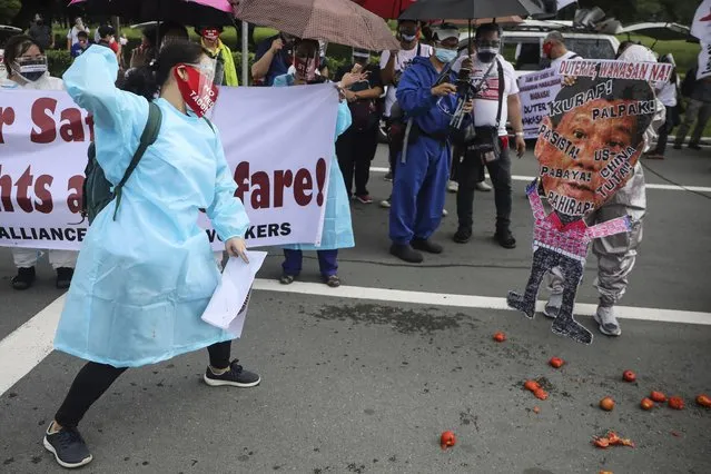 A protester hurls a tomato on a picture of Philippine President Rodrigo Duterte before marching towards the House of Representative where he is set to deliver his final State of the Nation Address in Quezon city, Philippines on Monday, July 26, 2021. Duterte is winding down his six-year term amid a raging pandemic and a battered economy. (Photo by Gerard Carreon/AP Photo)