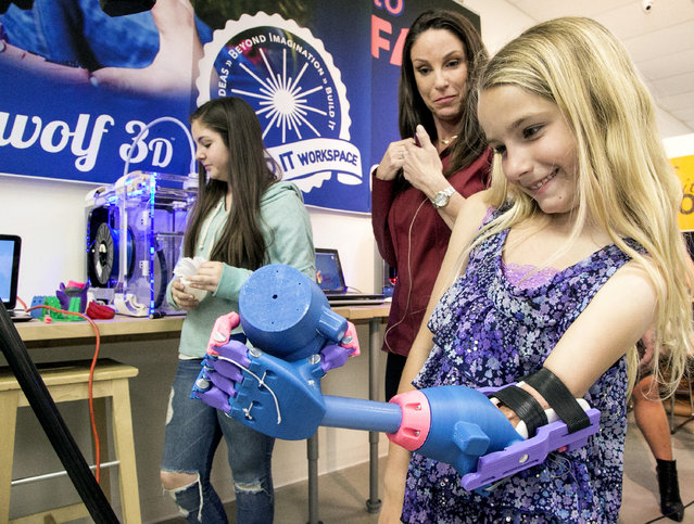 Faith Lennox, 7, right, smiles as she holds an extra plastic prosthetics part with her newly 3-D printed hand at the Build it Workspace in Los Alamitos, Calif., on Tuesday, March 31, 2015. At left, her aunt, Grace Stedman.  Build It Workspace is a 3-D printer studio that teaches people to use high-tech printers and provides access to them for projects. (Photo by Damian Dovarganes/AP Photo)