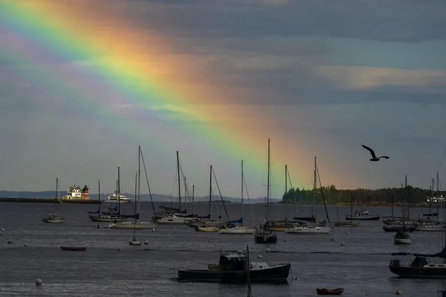 A rainbow colors the sky beyond the Rockland Harbor Breakwater Lighthouse following a brief rainstorm, Tuesday, August 1, 2023, in Rockland, Maine. (Photo by Robert F. Bukaty/AP Photo)