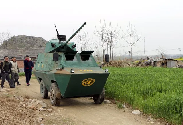 Villagers look on as a home-made armoured vehicle, built by local 35-year-old farmer Liu Shijie (in the vehicle), drives on a dirt road at a village in Huaibei, Anhui province April 7, 2015. It took Liu about six months and over 30,000 yuan ($4,850) to make the 5-metre-long, 3-metre-high vehicle from steel plates he purchased and pieces of a dismantled agricultural car, local media reported. (Photo by Reuters/Stringer)