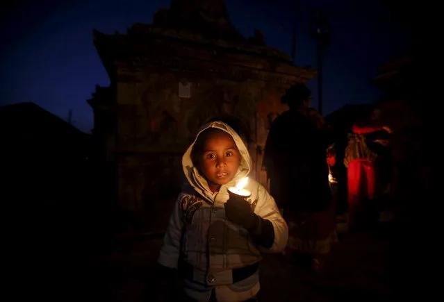 A child holding a butter lamp takes part in the Swasthani Bratakatha festival in Panauti near Kathmandu, Nepal, February 12, 2016. (Photo by Navesh Chitrakar/Reuters)