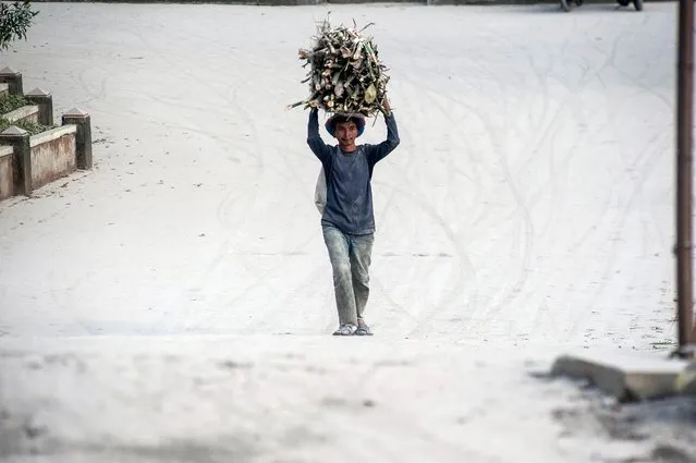 A villager walks along a path strewn with volcanic ash from the eruption of Mount Merapi, Indonesia's most active volcano, in Magelang near Yogyakarta on August 16, 2021. (Photo by Agung Supriyanto/AFP Photo)