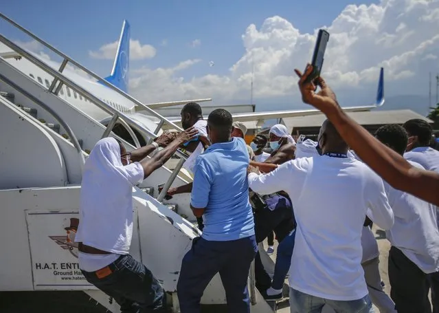 Haitians deported from the United States try to board the same plane in which they were deported, in an attempt to return to the United States, on the tarmac of the Toussaint Louverture airport in Port-au-Prince, Haiti Tuesday, September 21, 2021. (Photo by Joseph Odelyn/AP Photo)