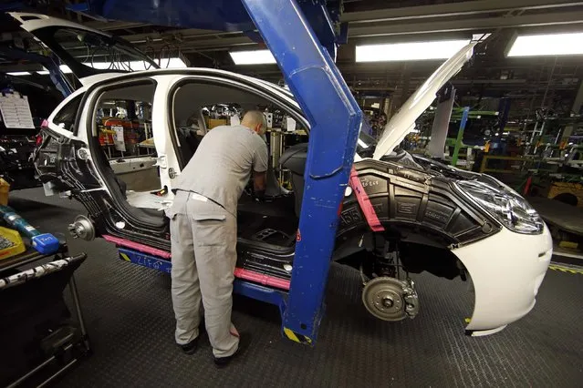 An employee works on the automobile assembly line of a Citroen C3 car at the PSA Peugeot Citroen plant in Poissy, near Paris, France, April 29, 2015. (Photo by Benoit Tessier/Reuters)