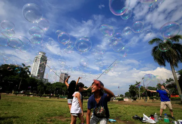 Children play with soap bubbles created by a street performer at Rizal park in Luneta, metro Manila, Philippines on May 16, 2018. (Photo by Romeo Ranoco/Reuters)