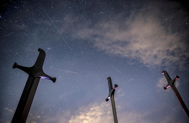 Meteors streak past stars in the night sky above the Battle of Didgori memorial complex during the annual Perseid meteor shower at Didgori, Georgia, August 13, 2021. (Photo by Irakli Gedenidze/Reuters)