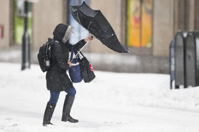 A woman's umbrella is turned inside-out by the wind as mixed winter precipitation falls Thursday, February 13, 2014, in Philadelphia. Snow and sleet are falling on the East Coast, from North Carolina to New England, a day after sleet, snow and ice bombarded the Southeast. (Photo by Matt Rourke/AP Photo)