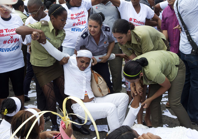 Policewomen drag away a member of Ladies in White, a women's dissident group that calls for the release of political prisoners, during their weekly protest in Havana, Cuba, Sunday, March 20, 2016. (Photo by Rebecca Blackwell/AP Photo)