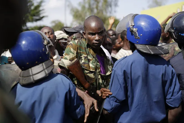 A soldier breaks through a police blockade as protesters march through the Musaga district of Bujumbura, in Burundi, Monday, May 11, 2015. (Photo by Jerome Delay/AP Photo)