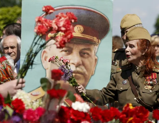 People lay flowers at the Tomb of the Unknown Soldier next to a portrait of Soviet leader Joseph Stalin during a ceremony commemorating the 70th anniversary of the end of the World War Two in Kiev, Ukraine, May 9, 2015. (Photo by Valentyn Ogirenko/Reuters)