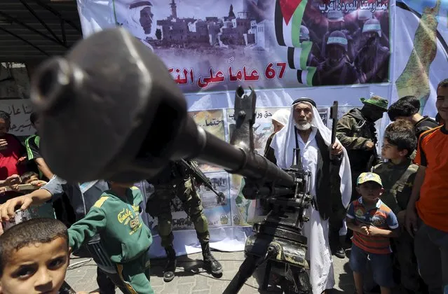 A Palestinian man holds a symbolic key as Hamas militants display a weapon during a rally after Nakba Day in Rafah in the southern Gaza Strip May 17, 2015. Palestinians mark “Nakba” (Catastrophe) on May 15 to commemorate the expulsion or fleeing of some 700,000 Palestinians from their homes in the war that led to the founding of Israel in 1948. (Photo by Ibraheem Abu Mustafa/Reuters)
