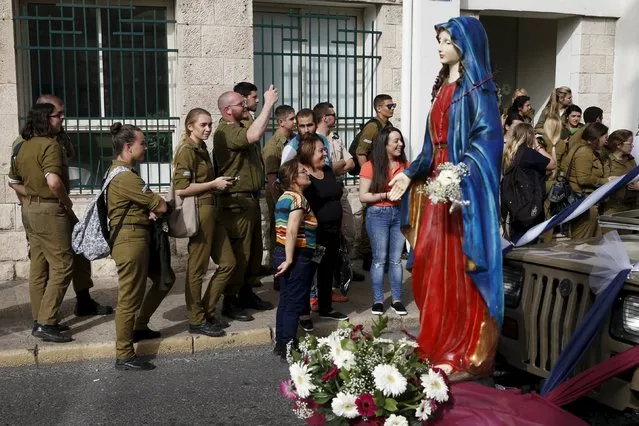 Israeli soldiers watch a statue depicting the Virgin Mary during a procession known as the “Holy Mary procession” in the northern Israel city of Haifa April 10, 2016. (Photo by Baz Ratner/Reuters)