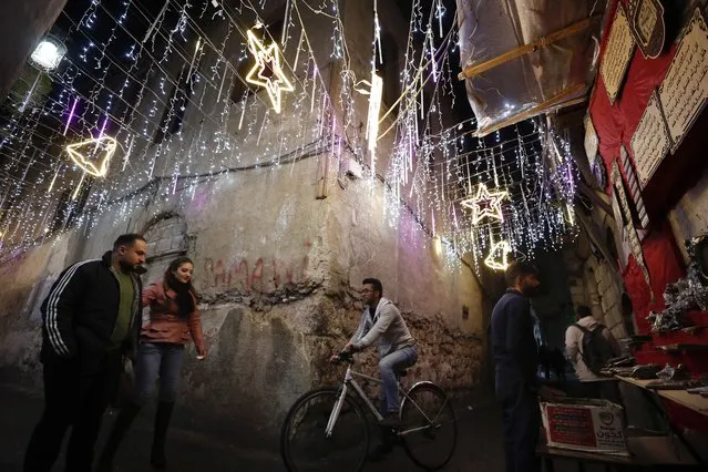 People walk in the Old City of Damascus, Syria, decorated for the upcoming Christmas holidays, Tuesday, December 14, 2021. (Photo by Omar Sanadiki/AP Photo)