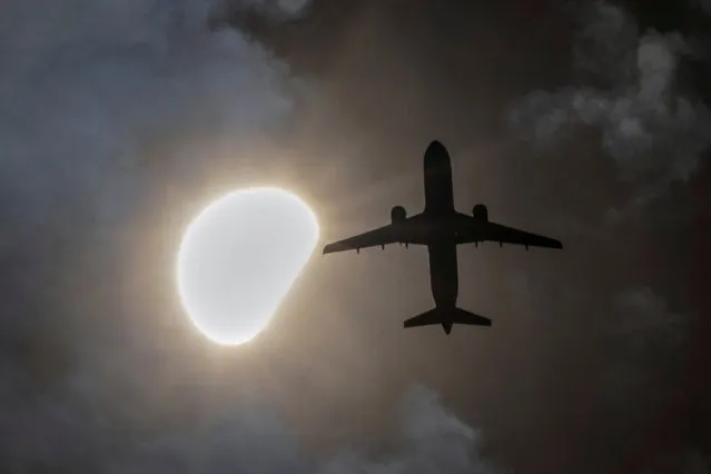 An airplane passes by the solar eclipse seen from Queens, New York City on April 8, 2024. (Photo by Andrew Kelly/Reuters)
