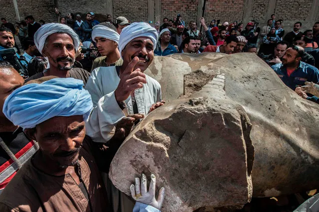 Egyptian workers pose next to an excavated statue, recently discovered by a team of German- Egyptian archeologists, in Cairo' s Mattarya district on March 13, 2017. (Photo by Khaled Desouki/AFP Photo)
