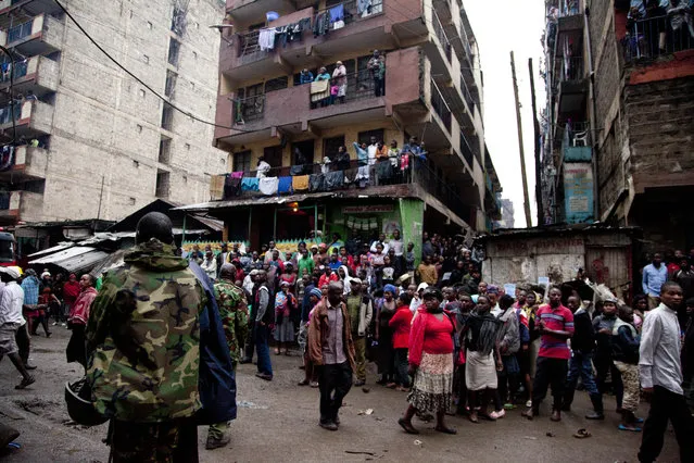 A police officer keep the crowd away at the site of a building collapse in Nairobi, Kenya, Saturday, April 30, 2016. (Photo by Sayyid Abdul Azim/AP Photo)