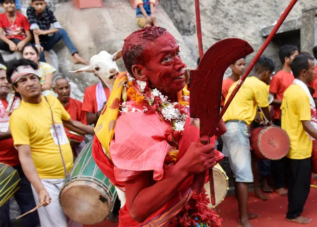 An Indian priest dances as he carries a sacrificial goat during the Deodhani Festival at the Kamakhya Temple in Guwahati, Assam, India on August 19, 2019. The three day Deodhani festival is held to worship the Serpent Goddess Kamakhya during which goats and pigeons are offered and sacrificed. (Photo by David Talukdar/Shutterstock)