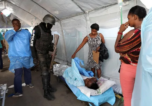 A police officer looks at a person who was injured when a fuel truck exploded in a neighbourhood during the night, in Cap Haitien, Haiti on December 14, 2021. (Photo by Ralph Tedy Erol/Reuters)
