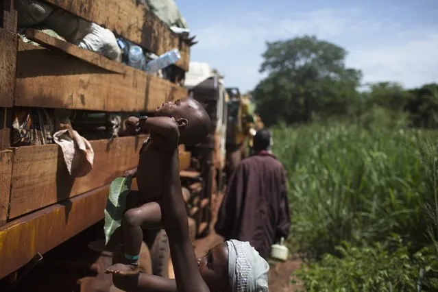 A woman passes her child on the top of a truck during a break from her journey towards Chad's border escorted by African Union operation in CAR (MISCA) a few kilometres after the northern town of Kaga Bandoro April 29, 2014. Of the remaining Muslims that have been sheltered from sectarian violence in the neighbourhood of PK12 in Bangui, over one thousand have been evacuated towards the northern town of Kabo and Sido on the border with Chad. (Photo by Siegfried Modola/Reuters)