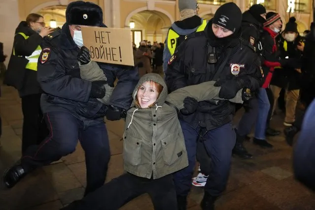 Police officers detain a demonstrator holding a sign reading “No war!” during an action against Russia's attack on Ukraine in St. Petersburg, Russia, Thursday, February 24, 2022. Hundreds of people gathered in the center of Moscow on Thursday, protesting against Russia's attack on Ukraine. Many of the demonstrators were detained. Similar protests took place in other Russian cities, and activists were also arrested. (Photo by Dmitri Lovetsky/AP Photo)