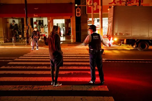 A police talks with a local resident on the street during an electric stoppage at the area after an earthquake in Tokyo, Japan on March 17, 2022. (Photo by Issei Kato/Reuters)