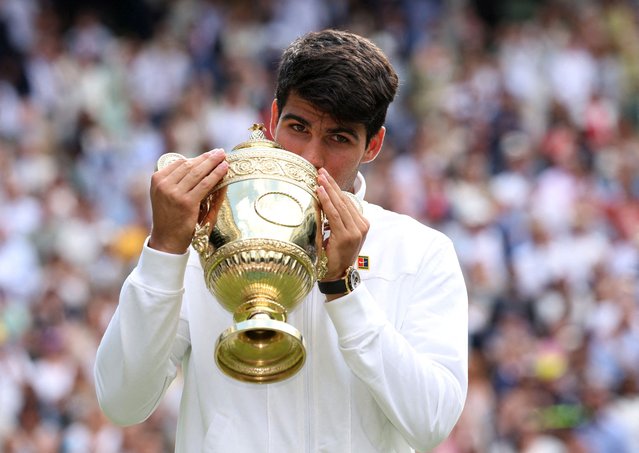 Spain's Carlos Alcaraz poses for a picture with the trophy after winning his men's singles final against Serbia's Novak Djokovic at the Wimbledon tennis championships in London on July 14, 2024. (Photo by Paul Childs/Reuters)