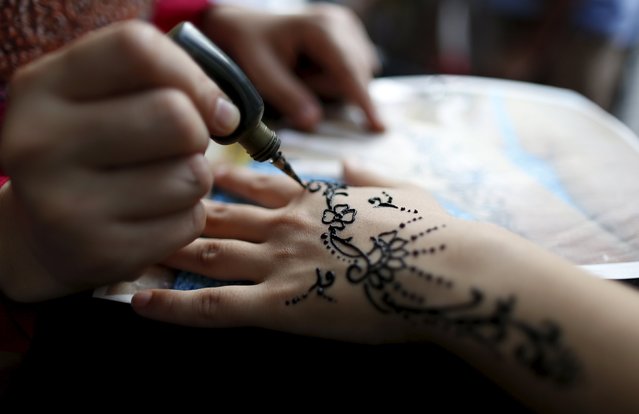 A girl gets her hands decorated with traditional henna patterns at a festival of Eid-al-Fitr to mark the end of the holy fasting month of Ramadan in Dortmund, Germany, July 17, 2015. (Photo by Ina Fassbender/Reuters)