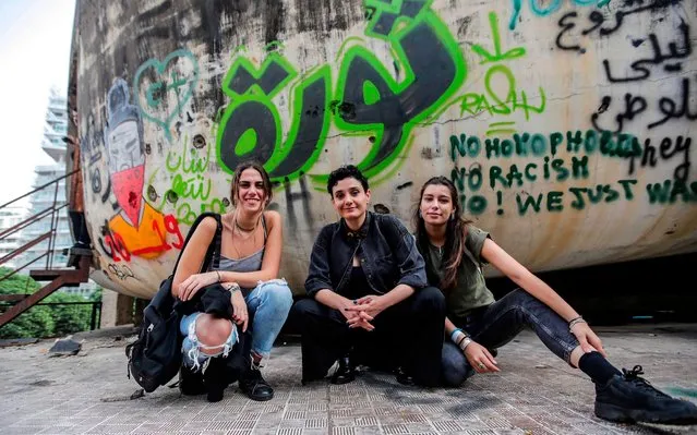 Lebanese women sit before graffiti reading in Arabic “revolution” drawn on the wall of the domed building in the centre of the capital Beirut known as “The Egg”, an unfinished cinema structure built in the 1960s, on October 24, 2019 amidst ongoing demonstrations against tax increases and official corruption. (Photo by Anwar Amro/AFP Photo)