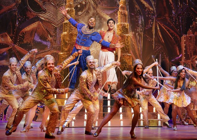 This image released by Disney Theatricals shows Michael James Scott as Genie, background left, and Adi Roy as Aladdin, background right, with the cast during a performance of the musical “Aladdin”. (Photo by Evan Zimmerman/Disney Theatricals via AP Photo)