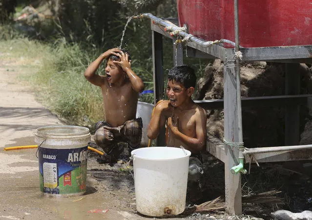 Iraqi displaced children cool themselves with water at a camp for internally displaced people in Baghdad's southern district of Dora on Tuesday, July 7, 2015. (Photo by Karim Kadim/AP Photo)