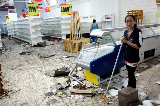 Workers clean the floor next to empty shelves and refrigerators in a supermarket after it was looted in San Cristobal, Venezuela May 17, 2017. (Photo by Carlos Eduardo Ramirez/Reuters)