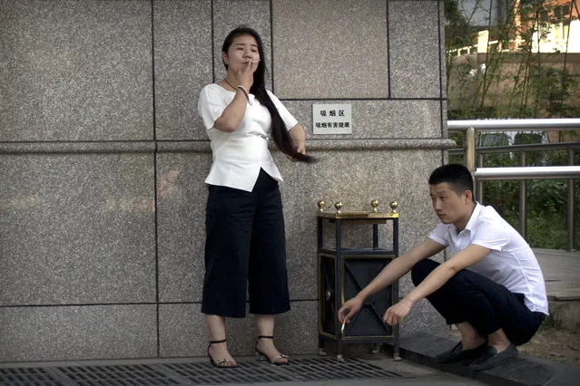 A man and a woman smoke cigarettes outside of an office building in Beijing, Wednesday, May 31, 2017. A decade-long study has found that most smokers in China, the world's largest consumer of tobacco, have no intention of kicking the habit and remain unaware of some of its most damaging health effects. (Photo by Mark Schiefelbein/AP Photo)