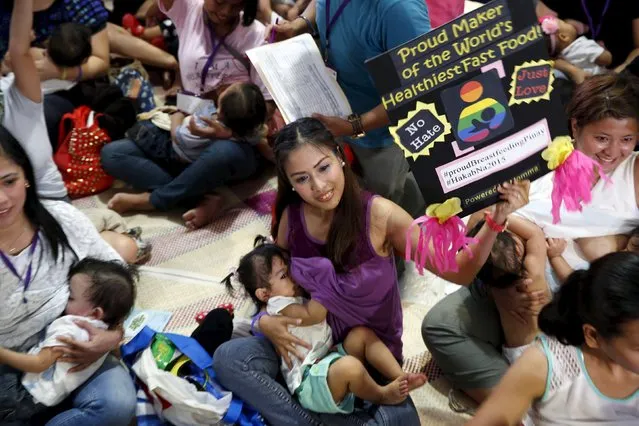 A mother displays a placard as she breastfeeds her child in Mandaluyong city, Metro Manila in the Philippines August 1, 2015. A statement from a non-government organization Breastfeeding Pinays said that in celebration of the National Breastfeeding Awareness Month in August, they organized a one day breastfeeding activity called “Hakab Na 2015”. (Photo by Erik De Castro/Reuters)