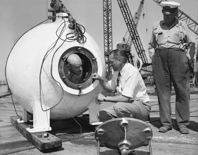 Otis Barton, who descent 3,028 feet in Beebe's bathysphere in 1934 off Bermuda, gets some final instruction from Dr. Maurice Nelles before being sealed into the bell of the University of Southern California Benthoscope at Long Beach, Calif., on June 20, 1949. (Photo by AP Photo)