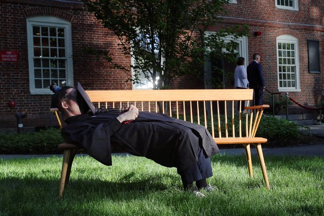 A student lies on a bench before Commencement Exercises for the classes of 2020 and 2021, which were originally not held in person because of the coronavirus disease (COVID-19) pandemic, in Cambridge, Massachusetts, U.S., May 29, 2022. (Photo by Brian Snyder/Reuters)